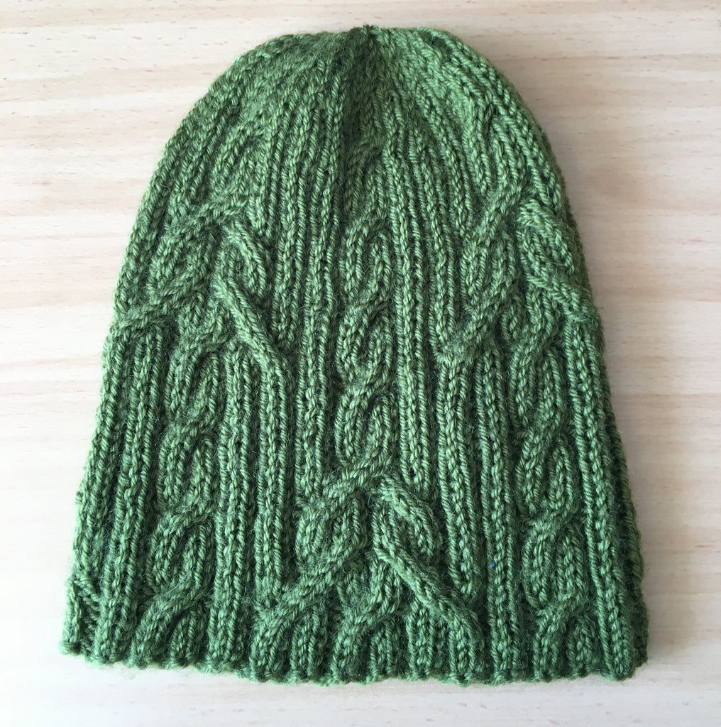 Green cabled hat laid flat on a table