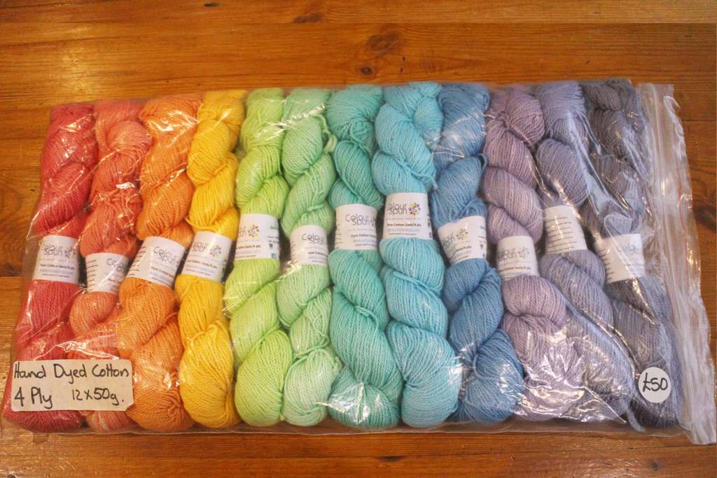 A colourful pack of 12 skeins of 4ply cotton, arranged as a rainbow
