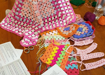 Colourful array of crocheted items and workbook as used in lessons at Crates of Wool