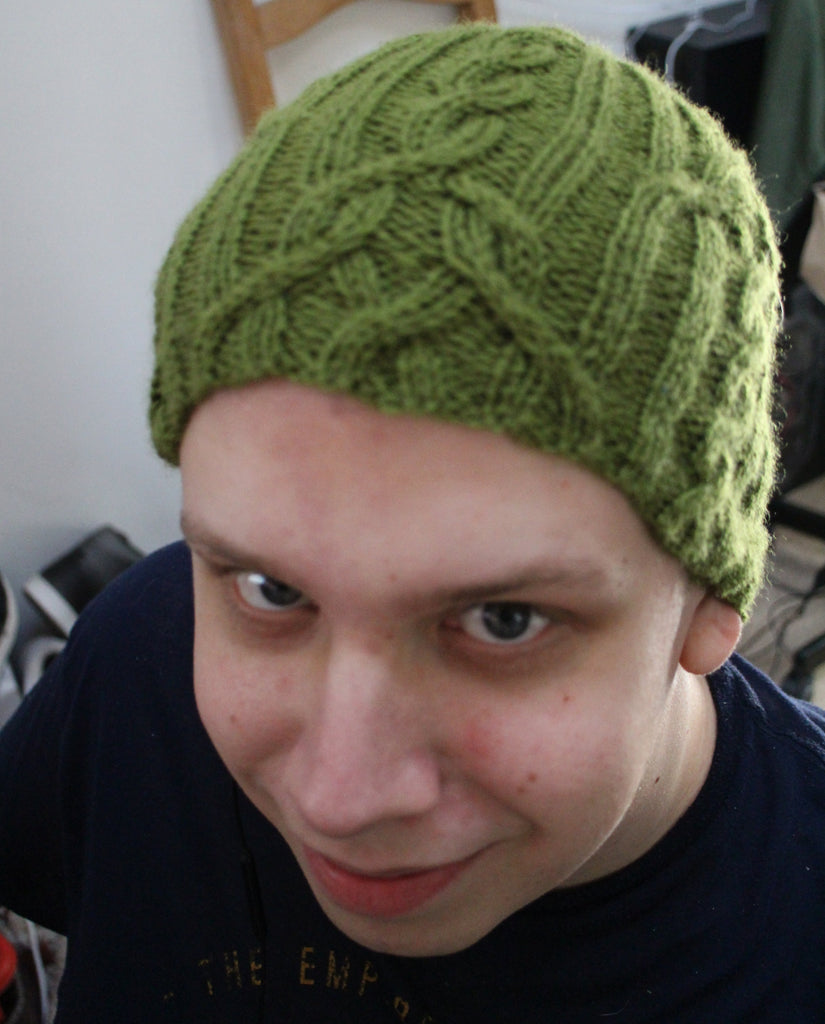 Young man wearing green cabled hat
